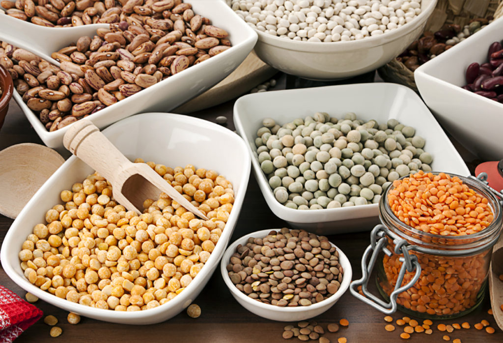 variety of legumes in bowls and glasses, arranged on kitchen table